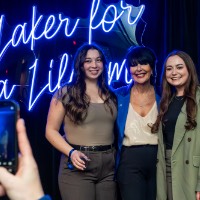 Girls in a brown shirt and a green blazer take a photo with President Mantella.